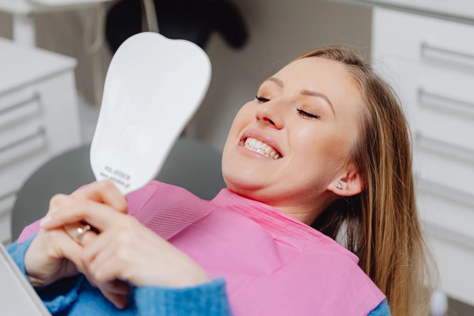 Patient checking her smile in the mirror, shown while covering All-on-6 Implants in Winnipeg