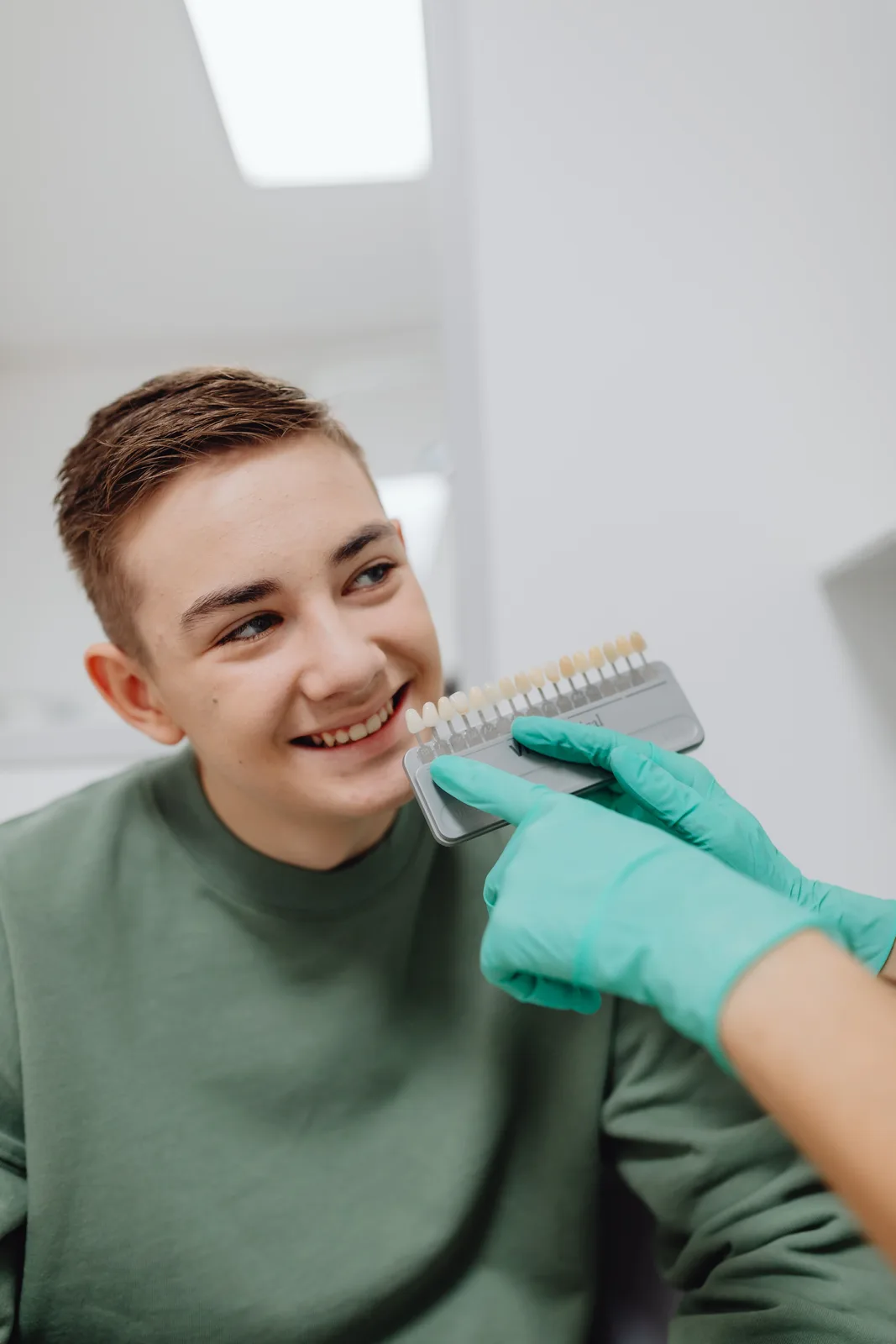 Shade guide held beside the patient smile, shown while covering Dentures Vs Implants in Winnipeg